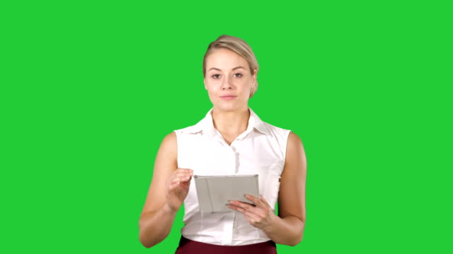 Hermosa-chica-sosteniendo-un-tablet-touch-pad-ordenador-gadget-pasar-páginas-y-mirando-en-la-cámara-en-una-pantalla-verde-Chroma-Key