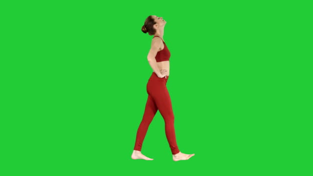 Beautiful-young-woman-stretching-her-neck-walking-on-a-Green-Screen,-Chroma-Key