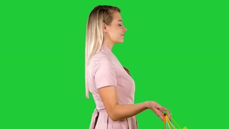 Let's-start-the-sale-shopping-Woman-in-pink-walking-with-shopping-bags-on-a-Green-Screen,-Chroma-Key