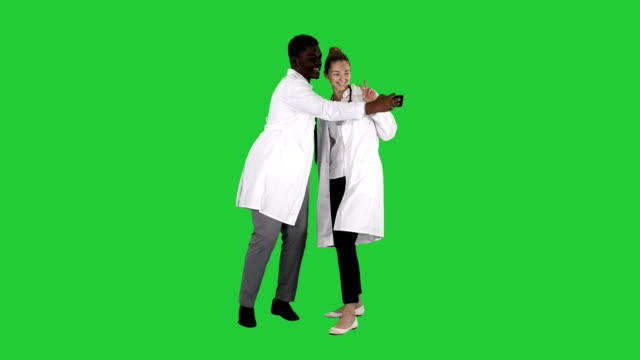 Zwei-Ärzte-machen-Selfie-per-Smartphone-und-lächelnd-auf-einem-Green-Screen,-Chroma-Key