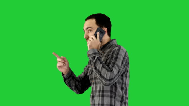 Retrato-de-parte-de-un-estudiante-feliz-caminando-y-hablando-por-celular-en-una-pantalla-verde-Chroma-Key