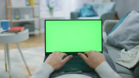 Woman-at-Home-Laying-on-a-Couch-using-Laptop-Computer-with-Green-Mock-up-Screen.-Girl-Typing-on-Computer,-Browsing-Internet,-Doing-e-Shopping.-Point-of-View-Camera-Shot.