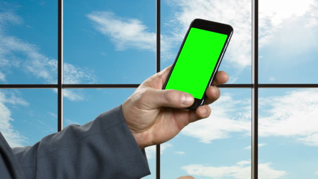 Man-with-smartphone-on-the-background-of-a-large-window.