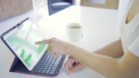 Joven-mujer-caucásica-en-sus-30s-utilizando-su-tablet-para-estar-en-línea-con-pantalla-verde