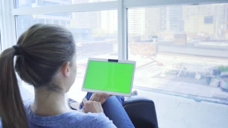 Young-caucasian-woman-in-her-30s-using-her-tablet-to-be-online-with-green-screen