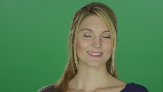 Schöne-Frau-lächelt,-zwinkert-und-bläst-einen-Kuss-auf-eine-Greenscreen-Studio-Hintergrund