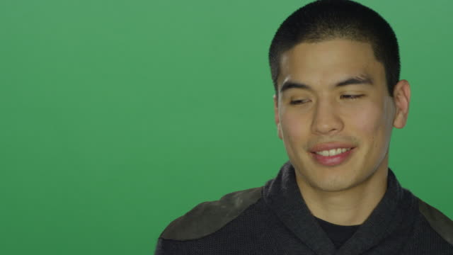 Young-man-begins-to-smile-after-being-sad,-on-a-green-screen-studio-background