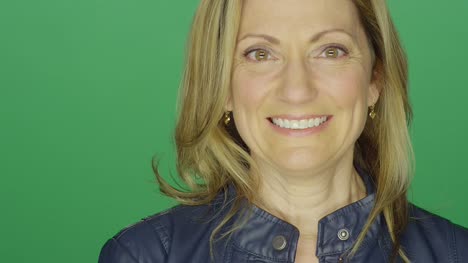 Schöne-mittlere-gealterte-Frau-lächelnd-auf-einem-green-Screen-Studio-Hintergrund,-Nahaufnahme