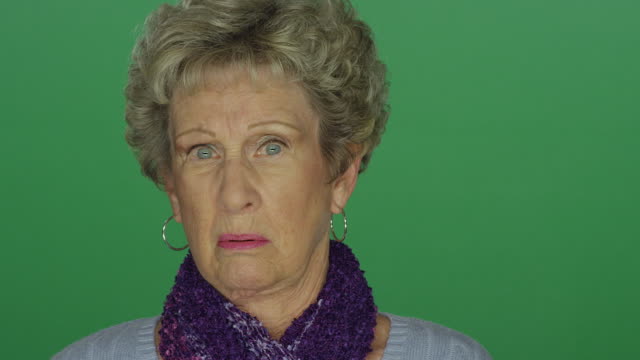 Older-woman-looking-shocked-and-appalled,-on-a-green-screen-studio-background