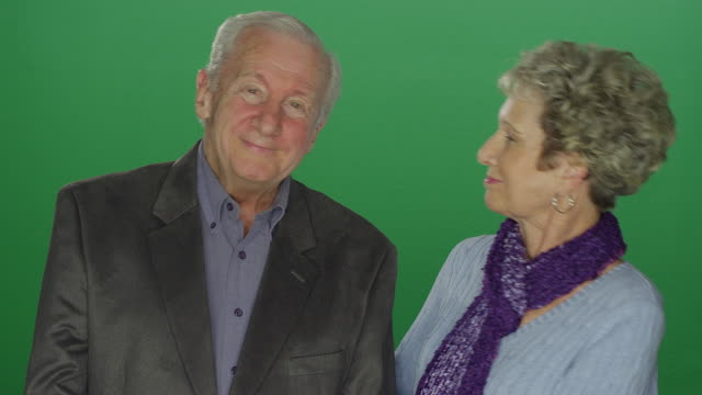 Elderly-woman-kisses-elderly-man,-on-a-green-screen-studio-background