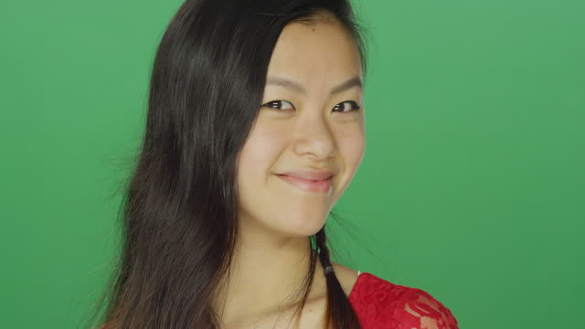 Mujer-asiática-joven-sonriendo-y-siendo-juguetón,-sobre-un-fondo-de-estudio-de-pantalla-verde