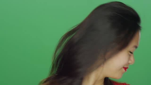 Young-Asian-woman-smiling-and-dancing,-on-a-green-screen-studio-background