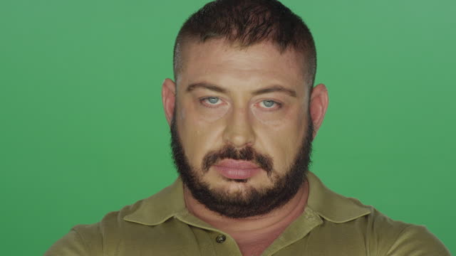 Muscular-man-staring-with-his-arms-crossed,-on-a-green-screen-studio-background