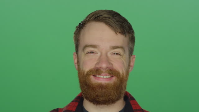 Young-bearded-man-laughs-and-smiles,-on-a-green-screen-studio-background