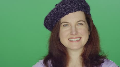 Junge-rothaarige-Frau-trägt-eine-Baskenmütze,-die-lächelnd-auf-einem-green-Screen-Studio-Hintergrund