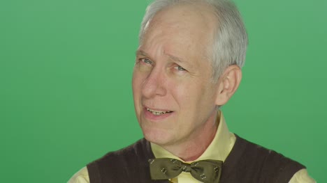 Ältere-Mann-lächelt-und-dann-zeigt-betreffen,-auf-einem-green-Screen-Studio-Hintergrund
