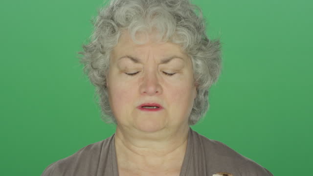 Ältere-Frau,-die-depressiv-aussieht,-auf-einem-grünen-Bildschirm-Studio-Hintergrund