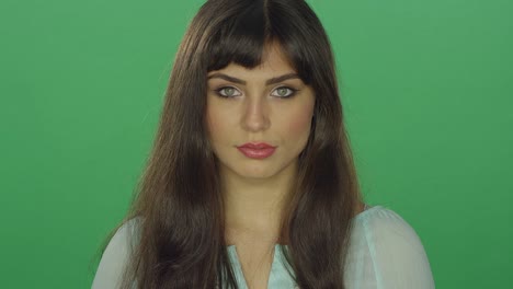 Beautiful-brunette-woman-staring-ahead,-on-a-green-screen-studio-background