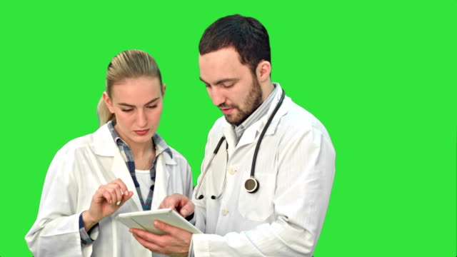Zwei-fachärztliche-Fachkräfte-diskutieren-über-eine-Behandlung-von-Patienten,-während-sie-ihre-Tablette-auf-einem-Green-Screen,-Chroma-Key,-verwenden