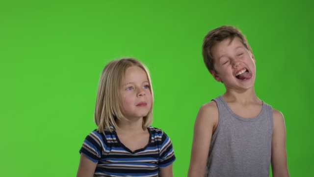 Dos-niños-haciendo-muecas-frente-a-greenscreen