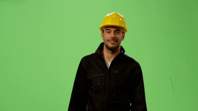 Bauarbeiter-in-einem-Schutzhelm-ist-zu-Fuß-auf-ein-Mock-up-green-Screen-im-Hintergrund.