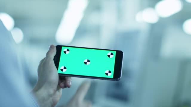 Worker-is-Using-Smartphone-with-Green-Screen-in-Landscape-Mode-in-Factory