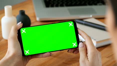 Person-using-cell-phone-with-green-screen-display-in-hand