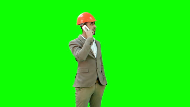 Contractor-in-hardhat-talking-on-his-cell-phone-on-a-Green-Screen,-Chroma-Key