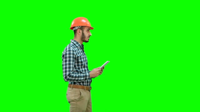 Auftragnehmer-Ingenieur-in-Bauarbeiterhelm-Inspektion-Baustelle-halten-digital-Tablette-auf-einem-Green-Screen,-Chroma-Key