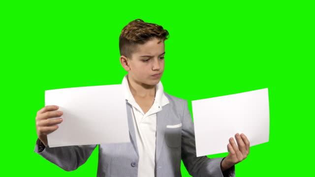 Düstere-Teenagerr-hält-zwei-Stück-von-Papieren-auf-grünem-Hintergrund