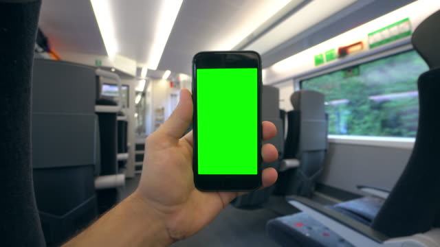 Hand,-die-eine-Handy-mit-einem-Green-Screen-auf-dem-Zug