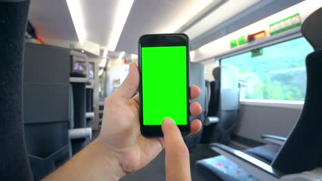 Mano-sosteniendo-un-teléfono-con-una-pantalla-verde-en-el-tren