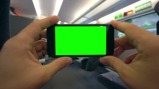 Manos-sosteniendo-un-teléfono-con-una-pantalla-verde-en-el-tren