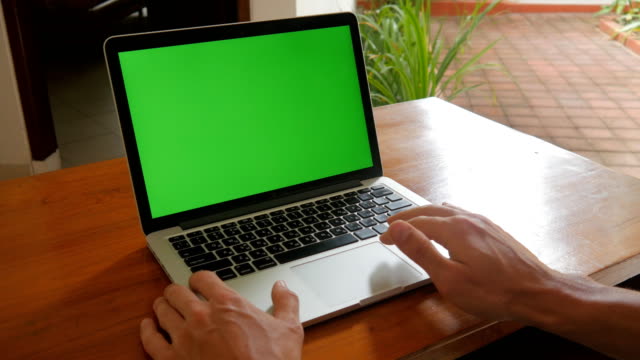 Hombre-trabaja-en-ordenador-portátil-en-casa-con-pantalla-verde.-Freelance-trabaja-en-casa.