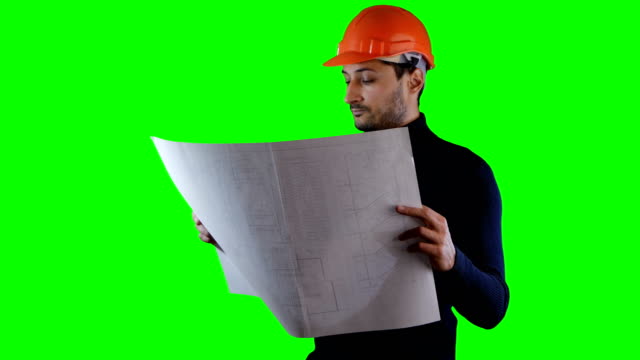 Un-hombre-de-casco-seguro-Lee-planos-en-la-pantalla-verde-de-fondo-clave-de-croma