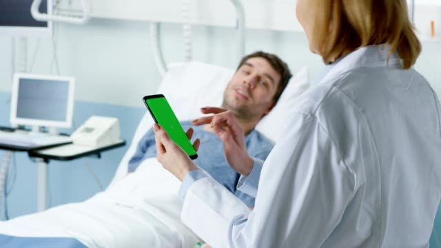 Professionelle-weibliche-Arzt-Gespräche-mit-kranken-Patienten-im-Bett-liegend,-nutzt-sie-Green-Screen-Handy.-Laser-und-Medizintechnik.