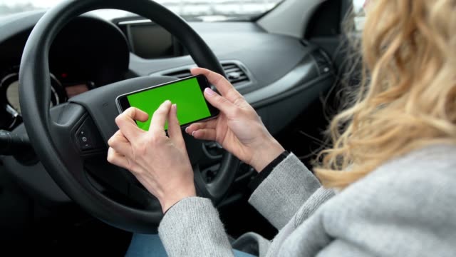 Frau-sitzt-in-das-moderne-Auto-und-mit-Smartphone---Closeup-Hände.-Green-Screen.-Chroma-key