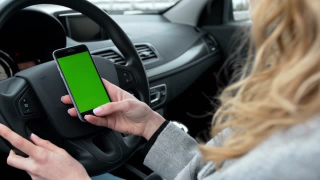 Woman-sits-in-the-modern-car-and-using-smartphone---closeup-hands.-Green-screen.Chroma-key