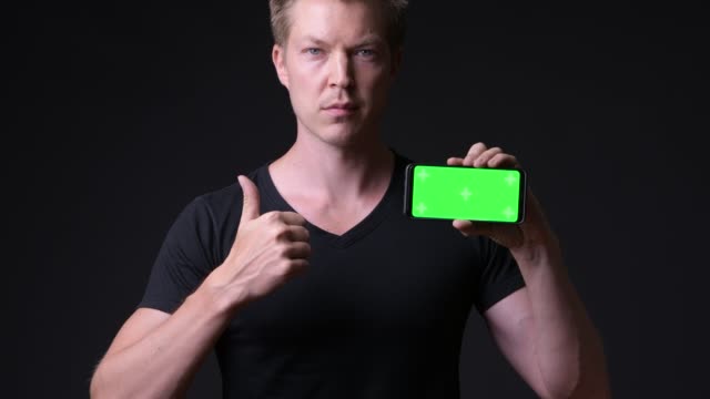 Hombre-que-sostiene-el-teléfono-móvil-con-pantalla-verde-clave-de-croma