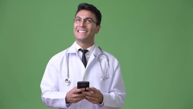 Junge-hübsche-Hispanic-Mann-Arzt-vor-grünem-Hintergrund