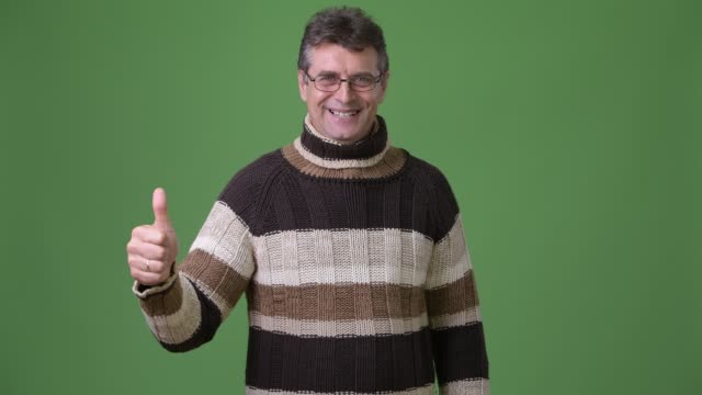 Reife-hübscher-Mann-mit-Rollkragenpullover-vor-grünem-Hintergrund