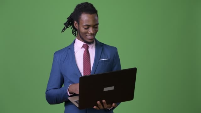 Young-handsome-African-businessman-with-dreadlocks-against-green-background