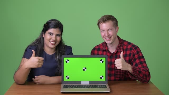 Young-multi-ethnic-business-couple-together-against-green-background