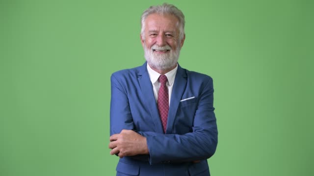 Handsome-senior-bearded-businessman-against-green-background