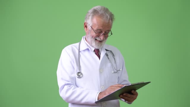 Hübscher-senior-bärtigen-Mann-Arzt-vor-grünem-Hintergrund