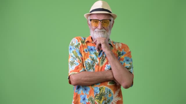 Gut-aussehend-Senior-bärtiger-touristischen-Mann-bereit-für-Urlaub-vor-grünem-Hintergrund