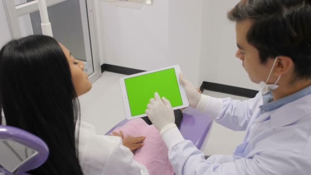 Dentist-explaining-procedure-to-patient-from-greenscreen-tablet