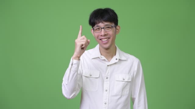 Young-happy-Asian-businessman-smiling-while-pointing-up
