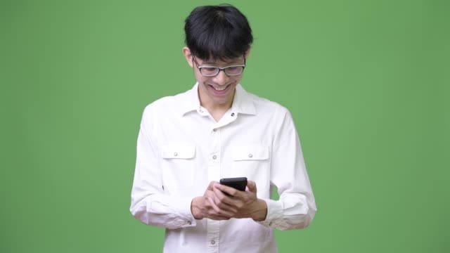Happy-young-Asian-businessman-smiling-while-using-phone