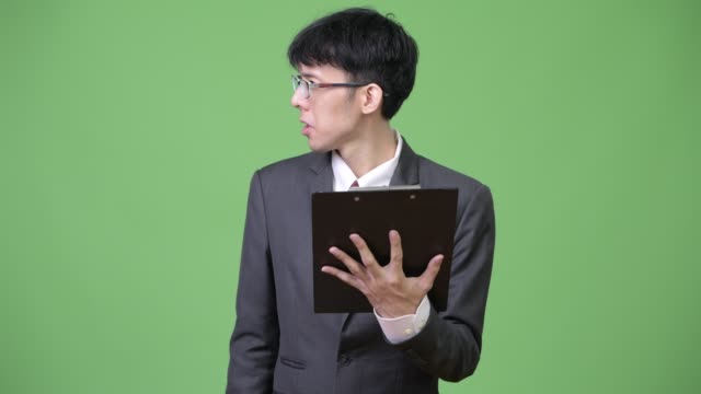 Joven-empresario-asiático-leer-con-portapapeles-y-hablar-con-el-lado